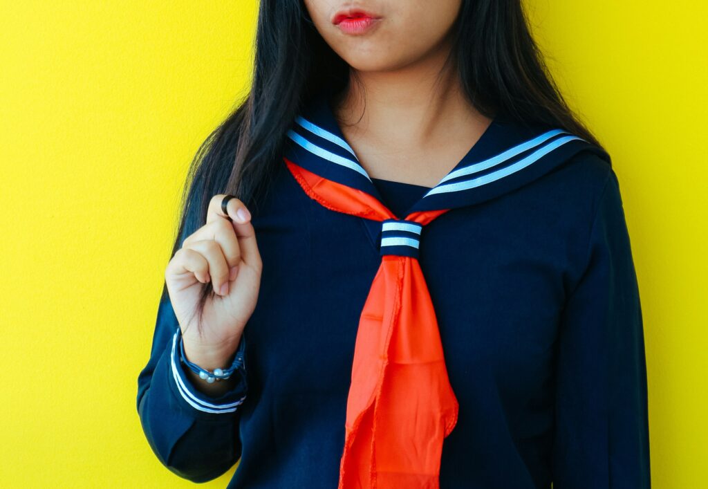 黄色い壁をバックにしたセーラー服の少女