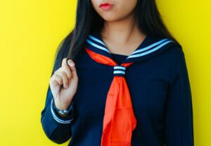 黄色い壁をバックにしたセーラー服の少女